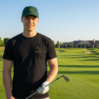 Man holding a golf club on a golf course with a clubhouse in the background